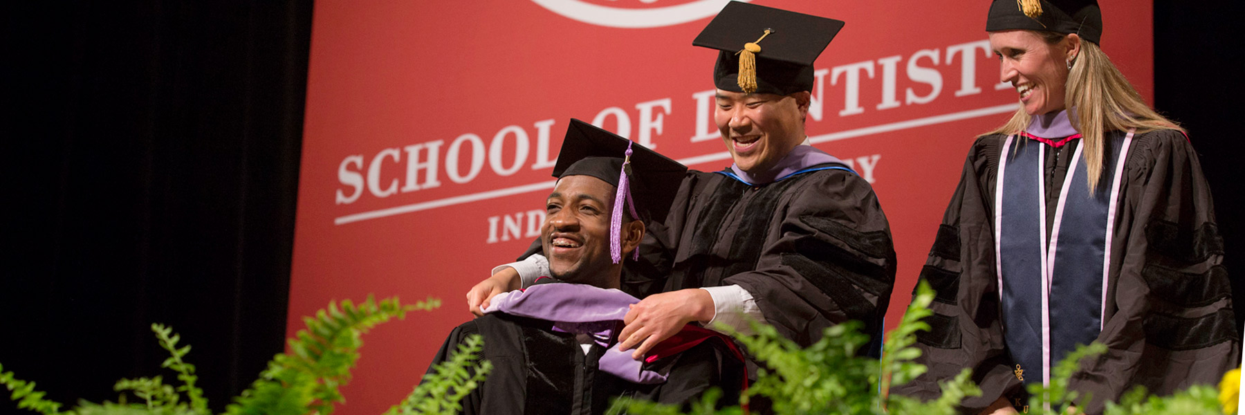 IU School of Dentistry faculty place a hood on a doctoral candidate.