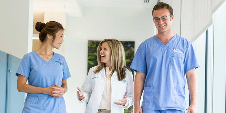 Three dentists walking down a hallway.